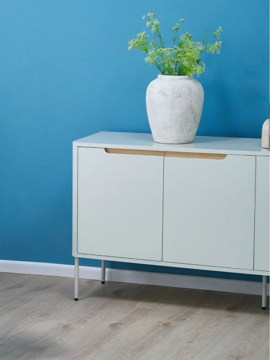 White sideboard cabinet with a wooden top and a plant