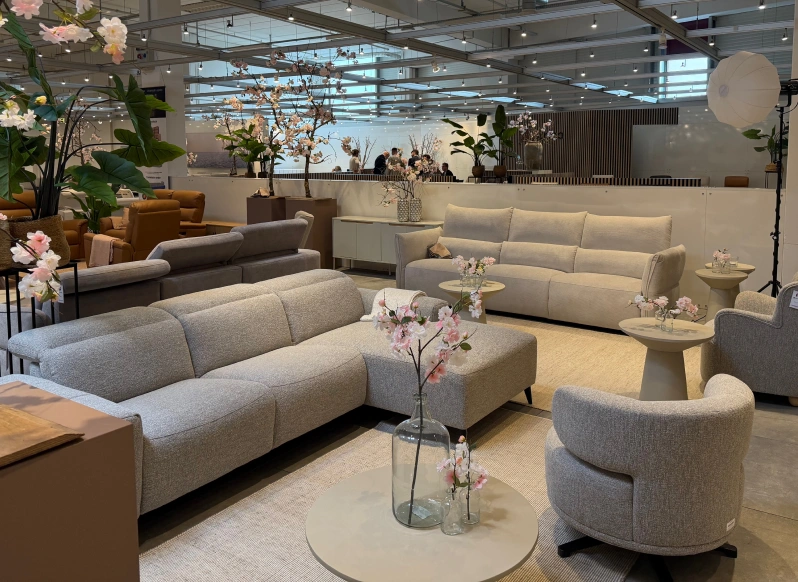 Furniture showroom with a light grey sofa and floral display