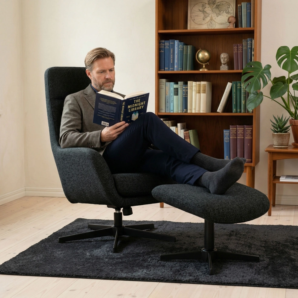 Man reading in a dark grey recliner chair with footstool